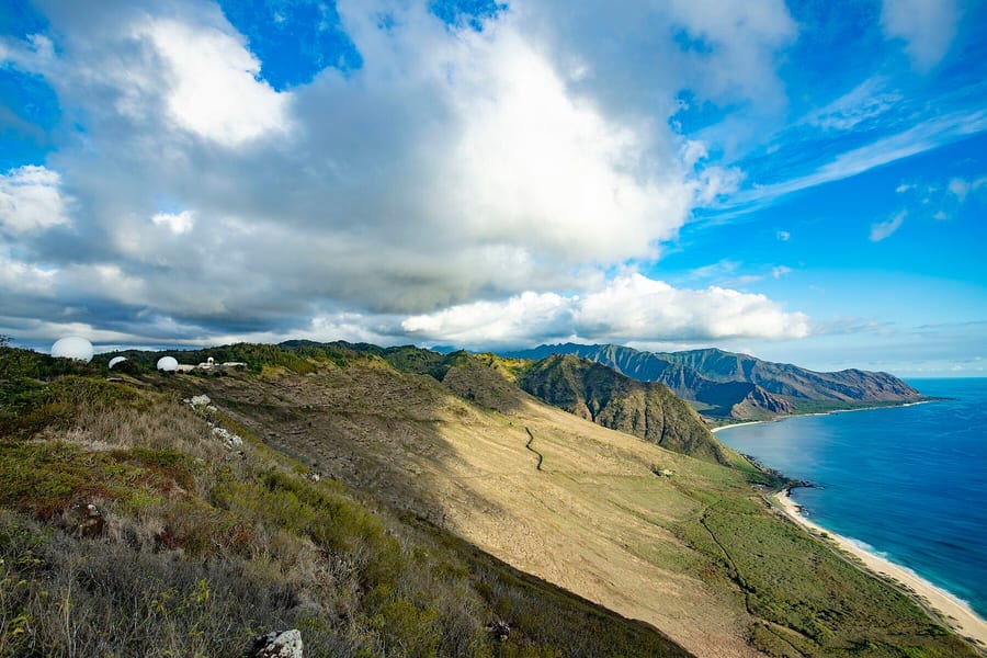 Aerial photograph of radomes on a ridge over the ocean.